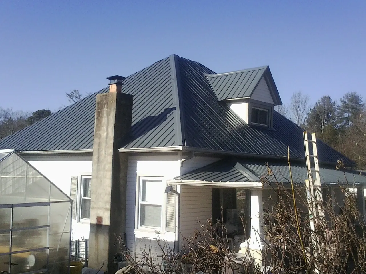 Dark blue standing seam metal roof on a white farmhouse with dormer — Slate & Tile Roof Repair by Roofing Brothers in Clallam Bay
