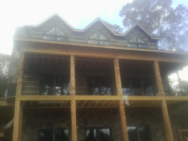 Dormers and porch framing on a large log home under construction — Roof Coating work by our crew in Clallam Bay