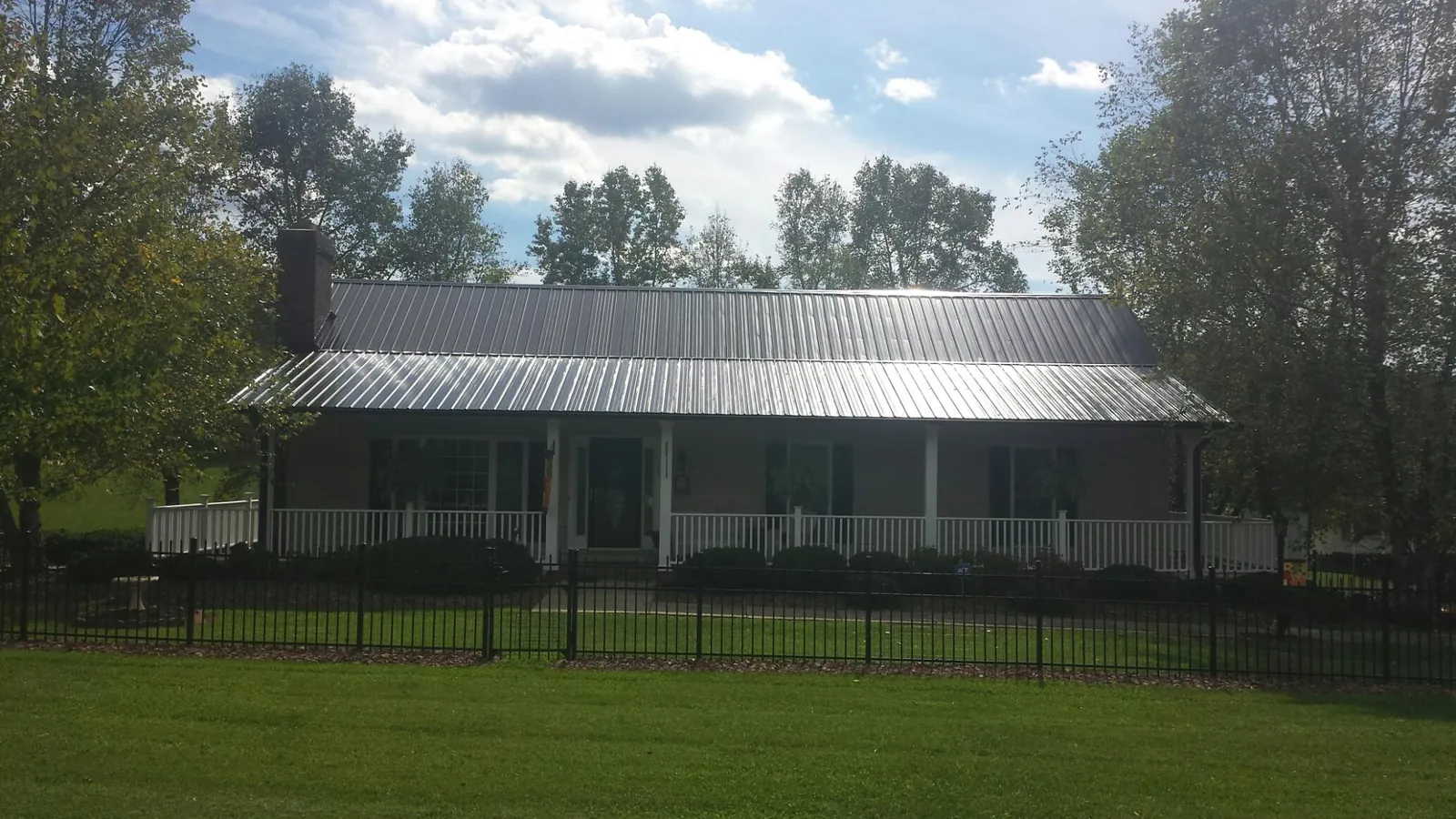 Gray metal roof on a brick ranch with a full width front porch — Gutter Guard Installation work by our crew in Clallam Bay
