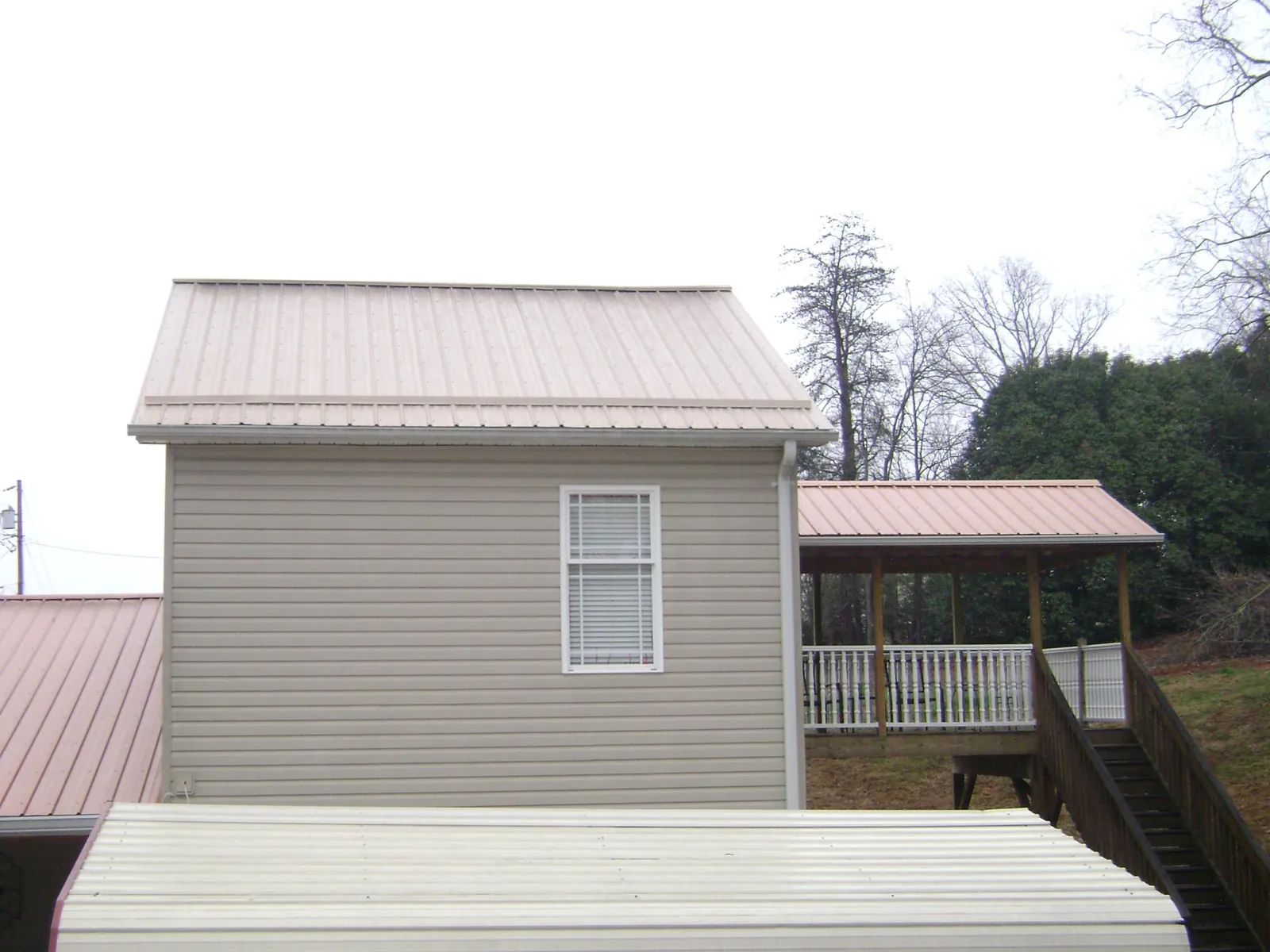 Tan metal roofs on a two story addition and attached porch, from a Roof Replacement job in Clallam Bay