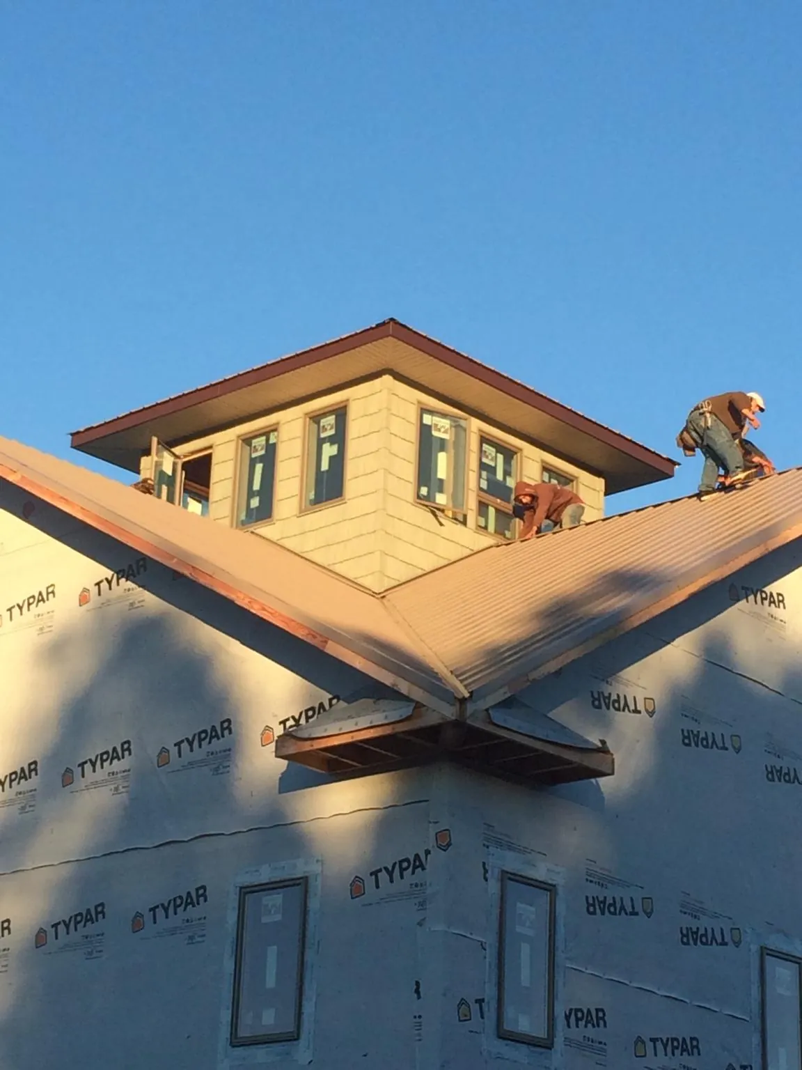 Roofers working around a rooftop cupola on a new metal roof at sunset — Roof Waterproofing in Clallam Bay by Roofing Brothers